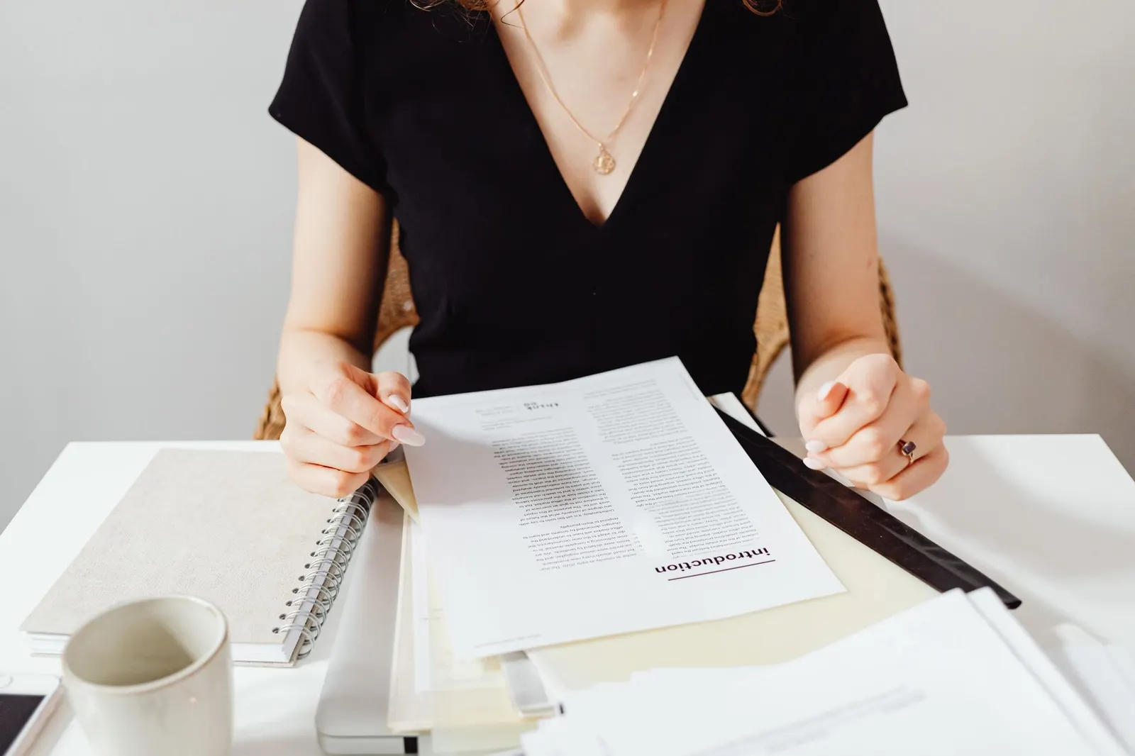 Woman sitting at a desk reviewing documents, featuring a casual work environment.